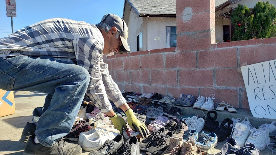caption: Jose Medina sets up rows of donated shoes and other goods for fire victims in front of his home of 40 years.