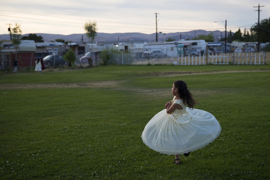 caption: Esmeralda Rosas, 5, twirls in circles outside of a mass wedding ceremony where 23 couples were married on Sunday, June 2, 2019, at Our Lady of the Desert Church in Mattawa.