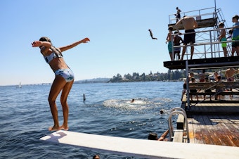 caption: A child jumps from the low dive at Laurelhurst Beach Club in Seattle on Monday, June 28, 2021. 