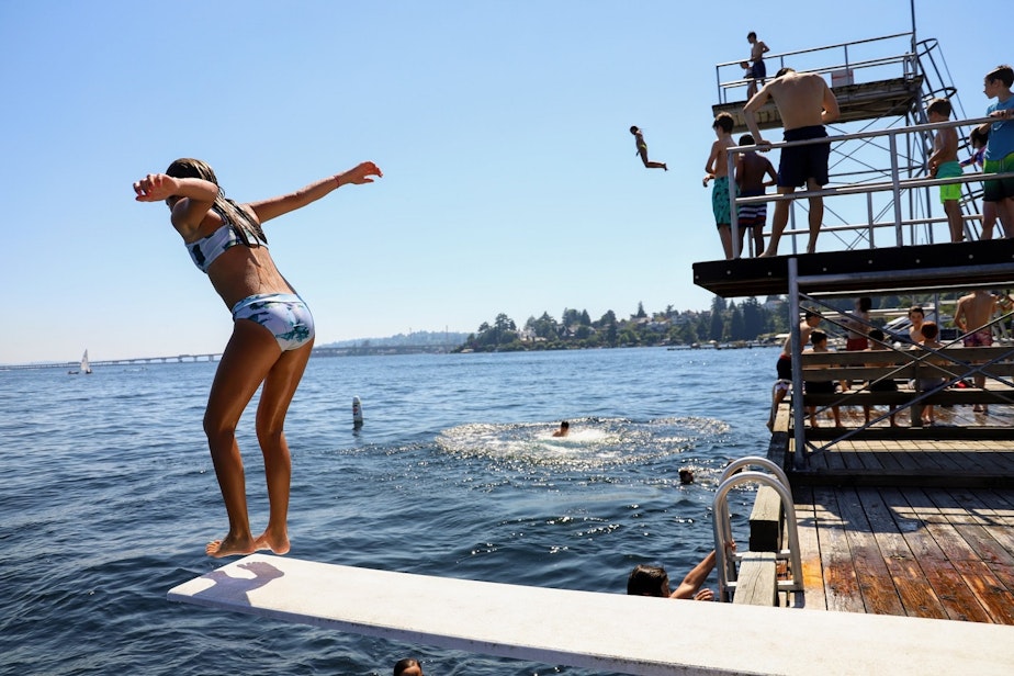 caption: A child jumps from the low dive at Laurelhurst Beach Club in Seattle on Monday, June 28, 2021.