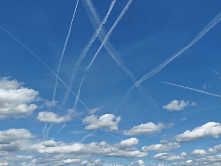 caption: Crisscrossing contrails and cumulus clouds.