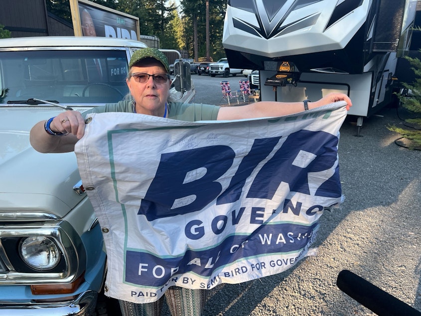 caption: Marty Mioni, a Kitsap County supporter of Semi Bird, holds up a flag she said was the first of many manufactured for the Republican candidate's gubernatorial campaign.