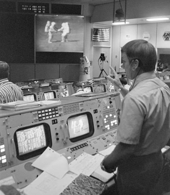 caption: A NASA flight manager watches the Apollo 15 astronauts as they work on the moon's surface.