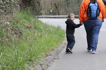 caption: Jessica and Blakely Tossey walk along Kent-Des Moines Road. The busy highway does not have sidewalks so Jessica wears a bright-colored sweatshirt. 