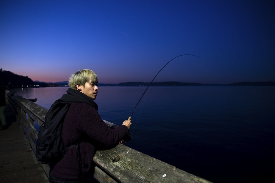 caption: Max, 26, squids on Friday, Nov. 17, 2023, from Les Davis Pier in Tacoma.