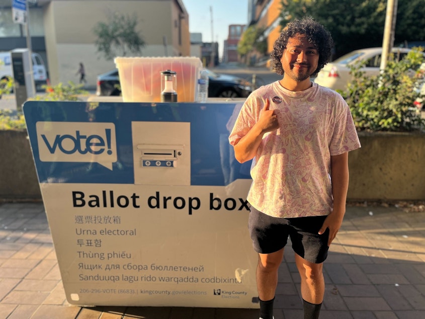 caption: Benji Covarrubias drops off his ballot for the 2024 primary election in Seattle's University District just after 7:30 p.m. on Tuesday.