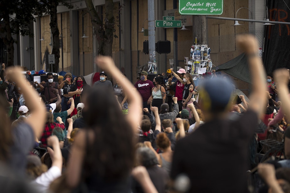 caption: A large crowd gathers at the intersection of East Pine Street and 12th Avenue to listen to speakers on Wednesday, June 10, 2020, in Seattle.