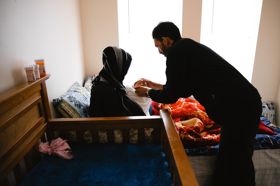caption: Adela, left, and Jabar Mahmoudi, right, care for their one-week-old son, Omar, on Monday, March 31, 2025, at their family members apartment in Kent.