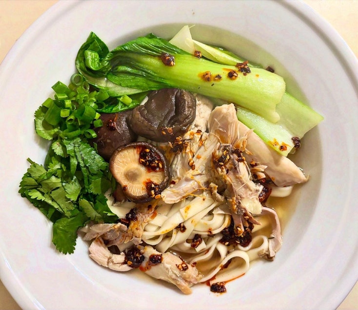 caption: KUOW Book Club guide Katie Campbell serves a bowl of long-life noodles in a Chinese-style chicken broth. The KUOW Book Club is reading and cooking with "Feasts of Good Fortune" by Hsiao-Ching Chou and Meilee Chou Riddle this month.