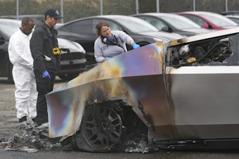 caption: ATF investigators and a member of the Seattle Fire Department inspect burned Tesla Cybertrucks at a Tesla lot in Seattle, Monday, March 10, 2025. 