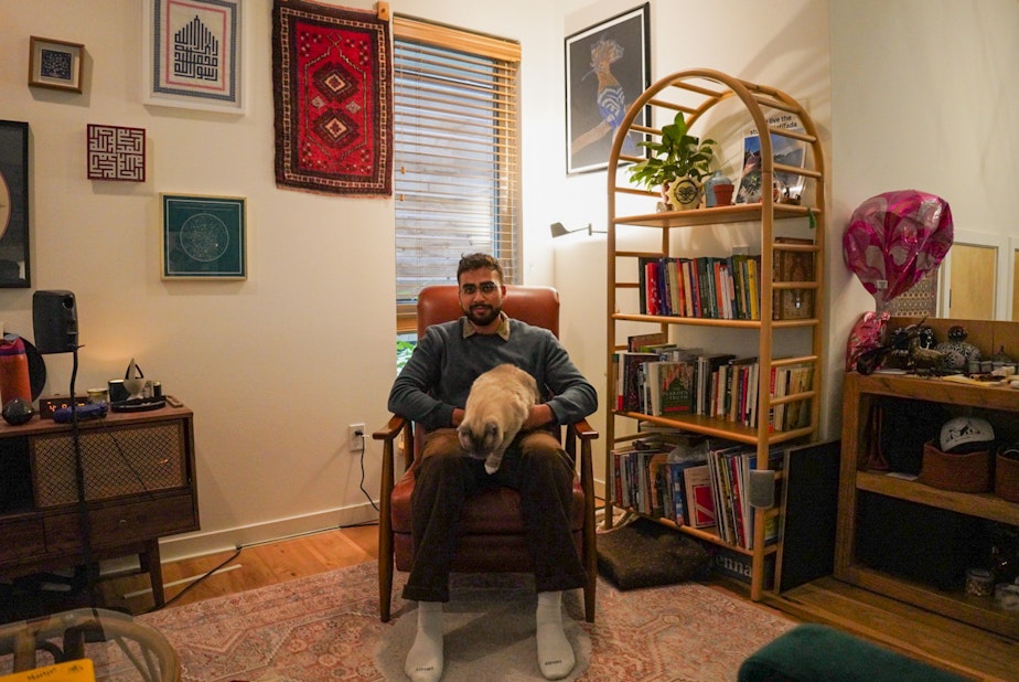caption: Pasha the cat, was one of the things Aysenur Eygi loved the most. To the right of Hamid Ali, above, the bookcase was an art creation of Eygi.