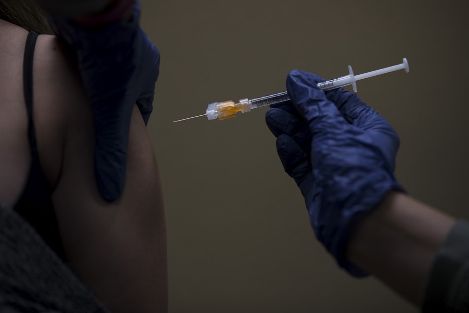 caption: Volunteer registered nurse Amy Rioux administers a Covid-19 vaccine on Wednesday, April 7, 2021, at Island Drug in Oak Harbor.