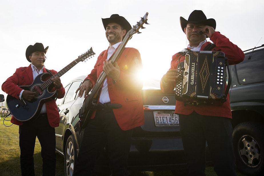 caption: Members of the Grupo Herradura De Plata from left, Fermin Herrera, Everardo Gallardo and Javier Cruz warm up in a parking area before performing during a mass wedding ceremony where 23 couples were married on Sunday, June 2, 2019, at Our Lady of the Desert Church in Mattawa.