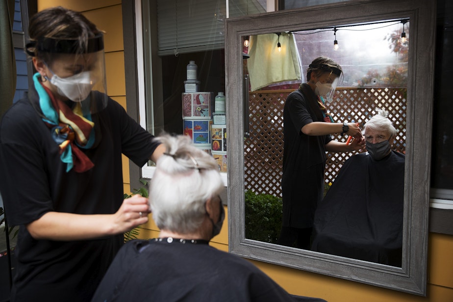 caption: Carter Renee cuts Alan Davidson's hair on Wednesday, October 21 , 2020, at the patio salon at their home in Seattle.