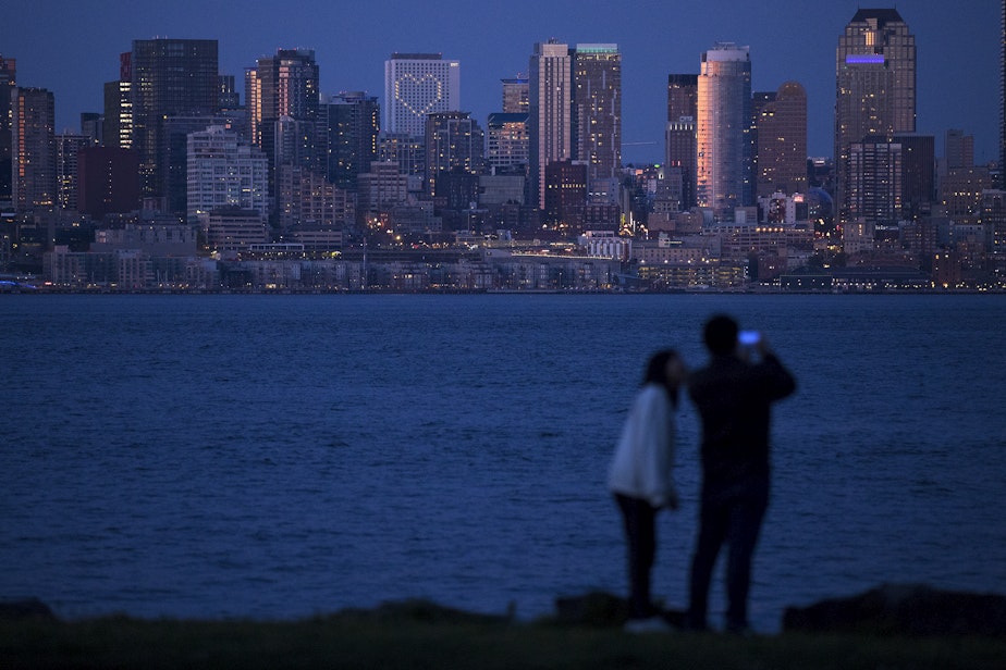 caption: Lit windows form the shape of a heart at the Hyatt Regency, visible from Sea Crest Park along Harbor Avenue Southwest on Wednesday, April 8, 2020, in Seattle.