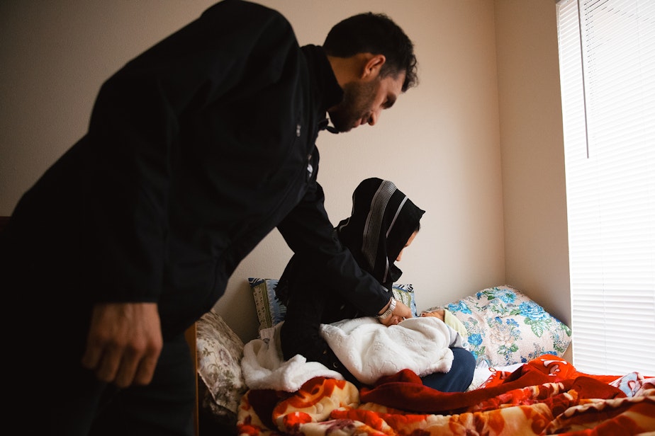 caption: Adela and Jabar Mahmoudi, left, care for their one-week-old son, Omar, on Monday, March 31, 2025, at their family members apartment in Kent.