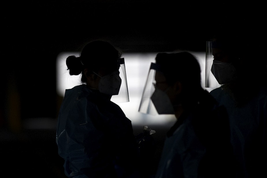 caption: QFC and Fred Meyer pharmacists wear face shields at a free drive-thru coronavirus testing site on Wednesday, May 13, 2020, in the parking garage at T-Mobile Park in Seattle.