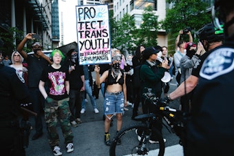 caption: Counter-protesters clash with Seattle police officers outside of the fundamentalist Christian group Mayday USA’s ‘Rattle in Seattle’ event, on Tuesday, May 27, 2025, at Seattle City Hall. The group advocates against trans rights. 