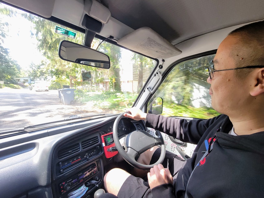 caption: Tuan Huynh's knees brush the dash of his Suzuki Carry while he drives. Huynh's daughters picked out panda fabric to decorate the interior.