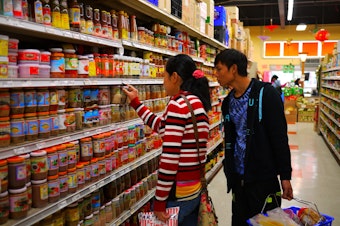caption: Newly arrived refugee Tu Tu gets a lesson in grocery shopping from his cousin, in Kent, Washington. Archive photo September, 2016.