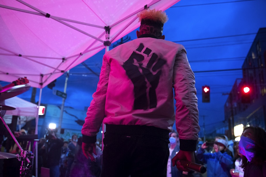 caption: Marshall Hugh performs with Marshall Law Band before a large crowd at the intersection of 12th Avenue and East Pine Street, outside of the Seattle police department's East Precinct building, on Saturday, June 13, 2020, in Seattle.
