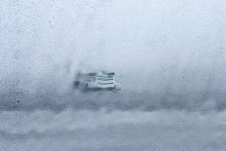 caption: A Washington state ferry approaches the Southworth ferry terminal, visible through heavy rain on a vehicle’s windshield, on Wednesday, February 5, 2025, in Southworth.