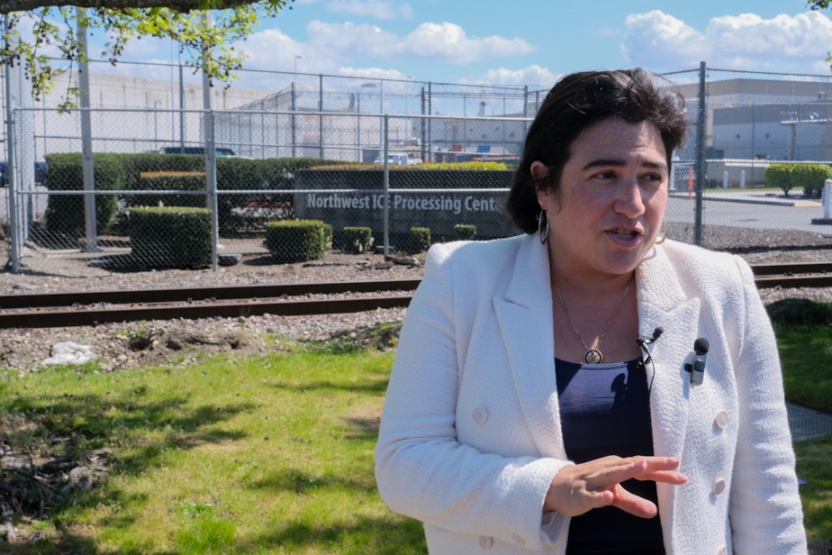 caption: U.S. Rep. Emily Randall, a Washington Democrat, speaks to press in front of the Northwest ICE Processing Center in Tacoma. This is her first time visiting the facility.
