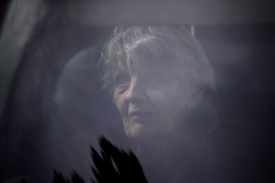 caption: Dorothy Campbell sits in her son, Charlie Campbell's vehicle, after knocking on her husband, Gene Campbell's window at Life Care Center of Kirkland and speaking to him through the phone, on Thursday, March 5, 2020, in Kirkland.