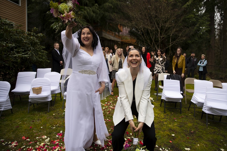 caption: Olena, left, and Iryna, right, smile while tossing bouquets to their wedding guests shortly after getting married on Saturday, April 8, 2023, at a home in Bellevue.