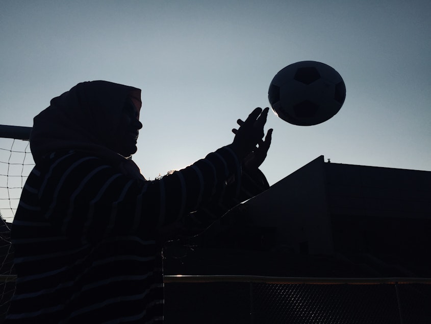 caption: A silhouette of Noor Aamir, tossing a soccer ball.