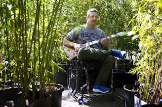 caption: Jon Schlueter is portrayed with his guitar at his home, and business, the Bamboo Collective Nursery, on Thursday, April 18, 2024, in Seattle’s Broadview neighborhood.