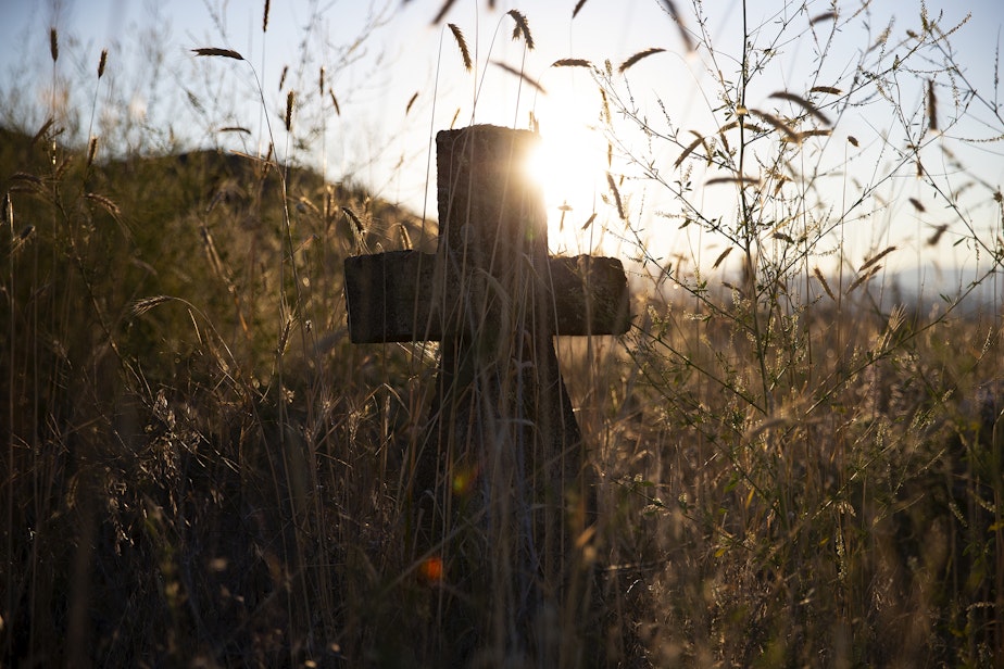 caption: An unmarked grave behind St. Mary’s Catholic Mission is shown on Thursday, July 20, 2017, in Omak.