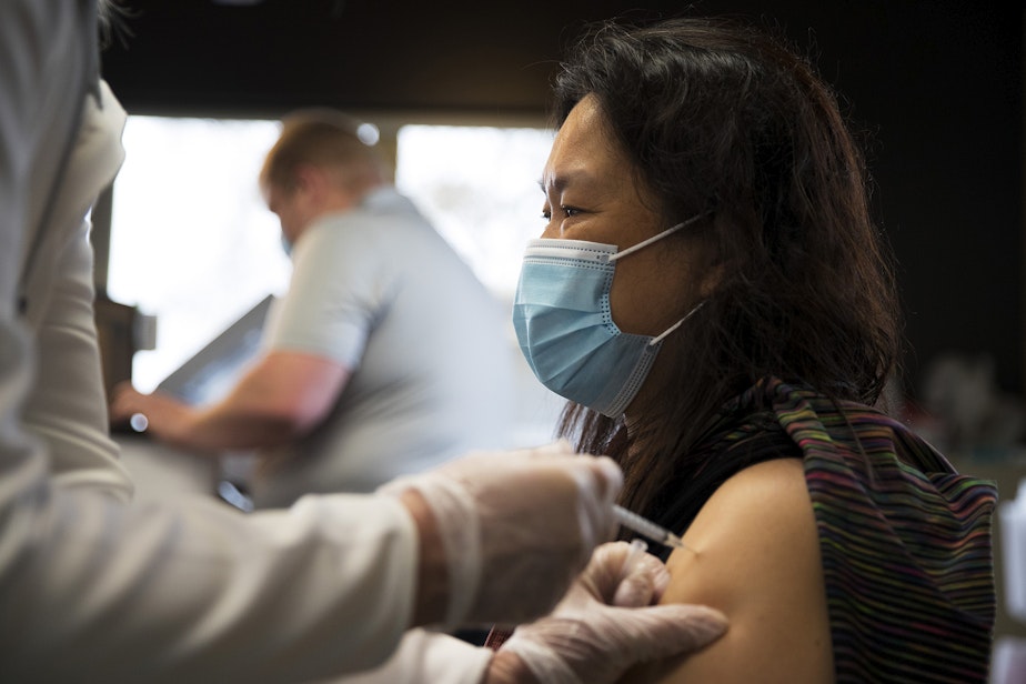 caption: Volunteer registered nurse Christine Marks administers a Covid-19 vaccine for Guo Huang on Wednesday, April 7, 2021, at Island Drug in Oak Harbor.
