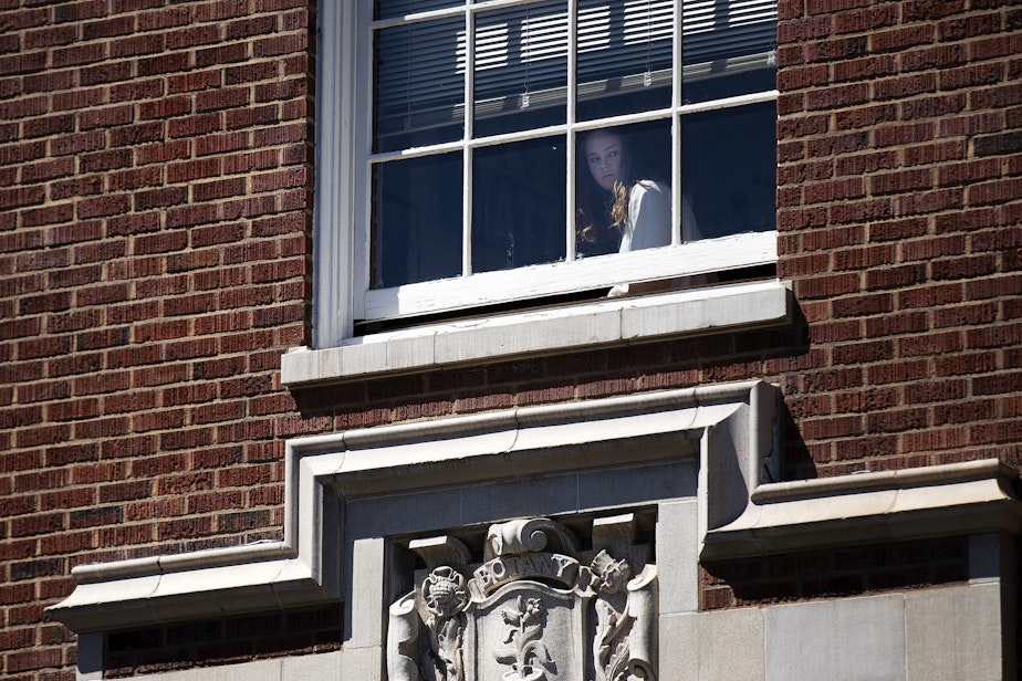 caption: A Garfield High School student looks out of a second floor classroom window during a lockdown following a deadly shooting on Thursday, June 6, 2024, in Seattle.