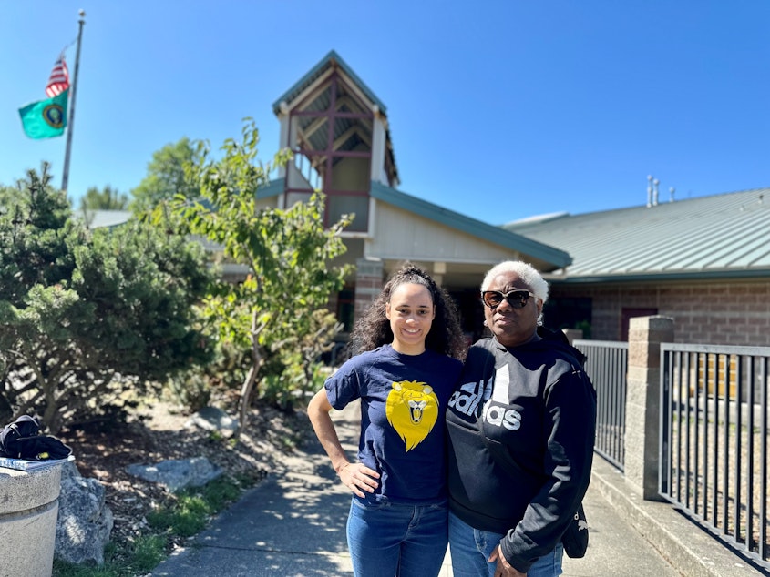 caption: Joy Anderson and her daughter Olivia Wilkinson stand in front of the former Cooper Elementary, which shuttered in 2009, during Seattle's last wave of school closures. The school now houses Pathfinder K-8.