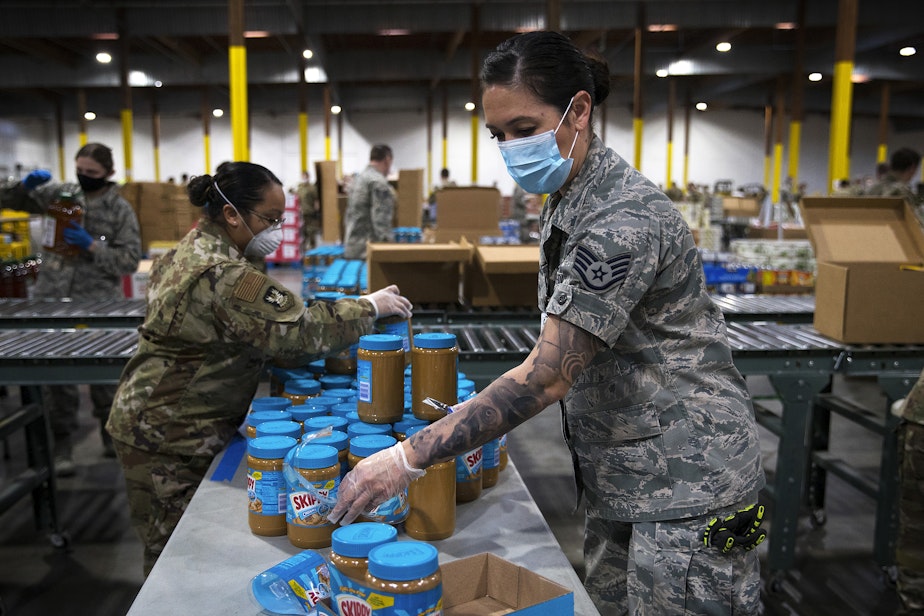 caption: Washington National Guard soldier Dahdia Hicks organizes jars of peanut butter along an assembly line of various food items on Tuesday, April 21, 2020, along East Marginal Way South in Seattle.