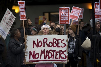caption: Anna Zwade, center, attends a rally to defend Roe v. Wade organized by councilmember Kshama Sawant on Tuesday, May 3, 2022, at Westlake Park in Seattle. 