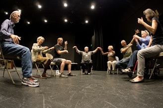 caption: Participants in an improv class at Seattle's Taproot Theatre Company pretend to be in an orchestra.