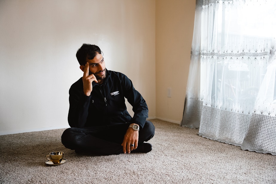 caption: Jabar Mahmoudi sits in the living area of his brother-in-law’s apartment on Monday, March 31, 2025, in Kent.