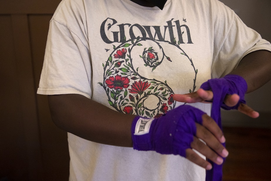 caption: Durojaiye Heru gets ready for boxing class on Wednesday, July 17, 2024, at Washington Hall in Seattle.