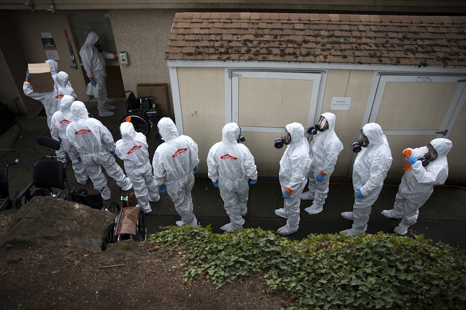 caption: Members of a Servpro cleaning crew line up before entering the Life Care Center of Kirkland, the long-term care facility at the epicenter of the first coronavirus outbreak in the U.S., on Wednesday, March 11, 2020, in Kirkland.