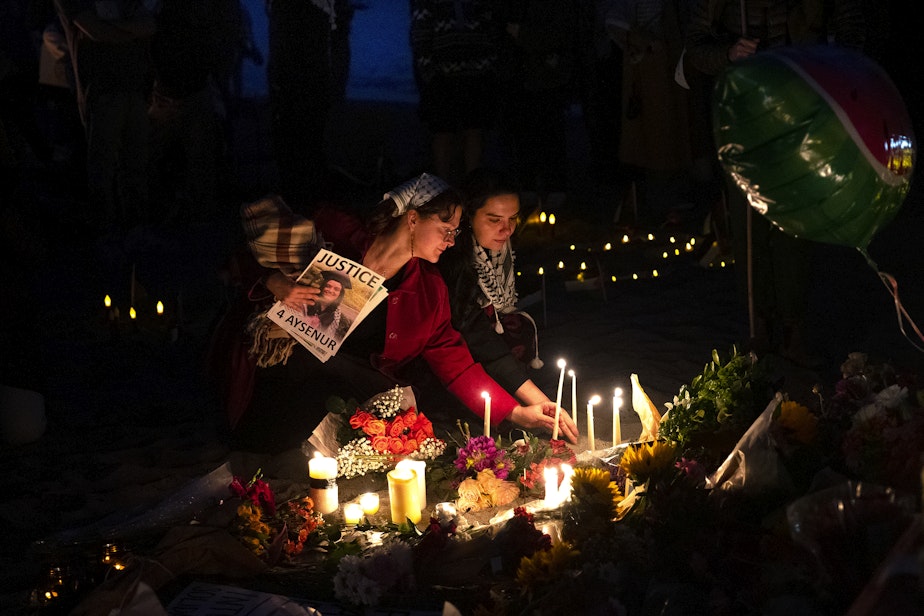 caption: Ludmela, left, and Jo, right, place candles at a vigil for Aysenur Ezgi Eygi, a 26-year-old Turkish American activist who was killed by Israeli soldiers while participating in an anti-settlement protest in the occupied West Bank, on Wednesday, September 11, 2024, at Alki Beach Park in Seattle.
