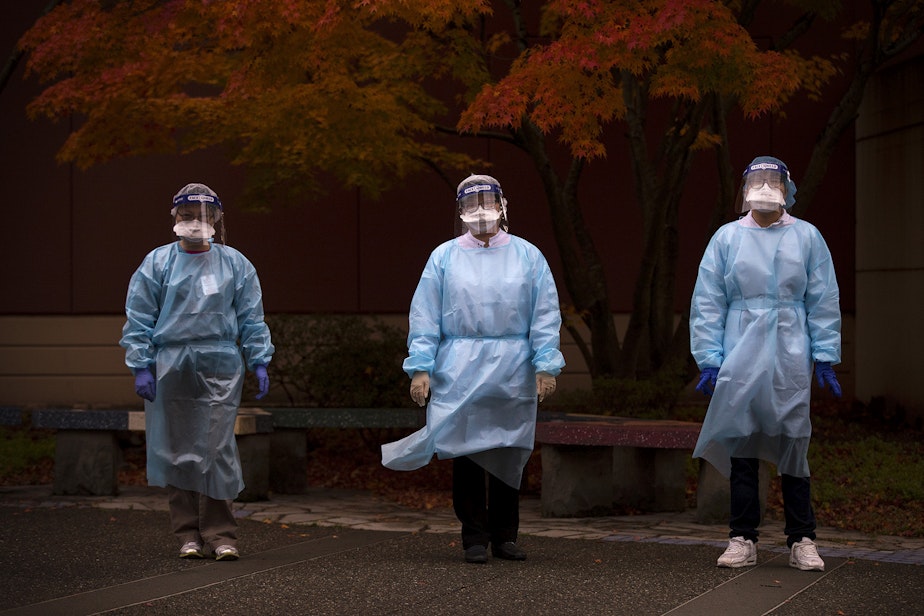 caption: From left, registered nurse Shu Kuang, registered nurse Tina Nguyen and patient services representative Denny Ho stand for a portrait following a shift of Covid-19 testing on Friday, November 20, 2020, at the International Community Health Services drive thru testing site on 8th Avenue South in Seattle's International District.