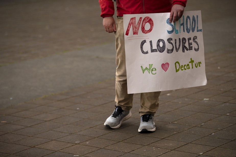 caption: Kevin Krouse holds a sign advocating for no school closures during an ‘All Together for Seattle Schools’ rally on Tuesday, May 28, 2024, at Roosevelt high school in Seattle.