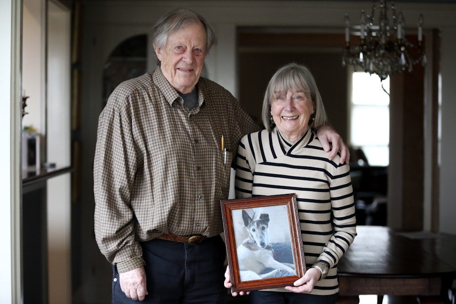 caption: Leonard and Pam Johnson hold a photo of their dog, Django, who passed away last week. Leonard "Ned" Johnson is one of the people identified by the Social Security Administration as dead, even though he is alive and well and living in Seattle.