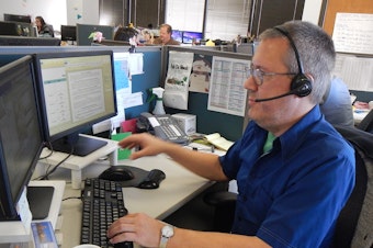 caption: Alex Williams, an operator for 211, King County's information line for emergency food or shelter.