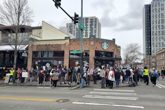 caption: Starbucks Workers United rally outside the University District Starbucks March 11 in Seattle. Workers were demanding a fair contract and decrying union busting by the coffee giant.