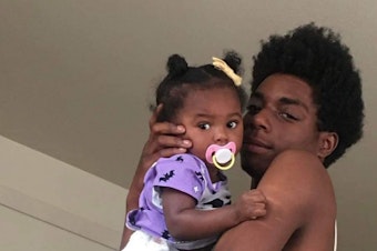 caption: Saylen Kelly, 18, with his daughter. 