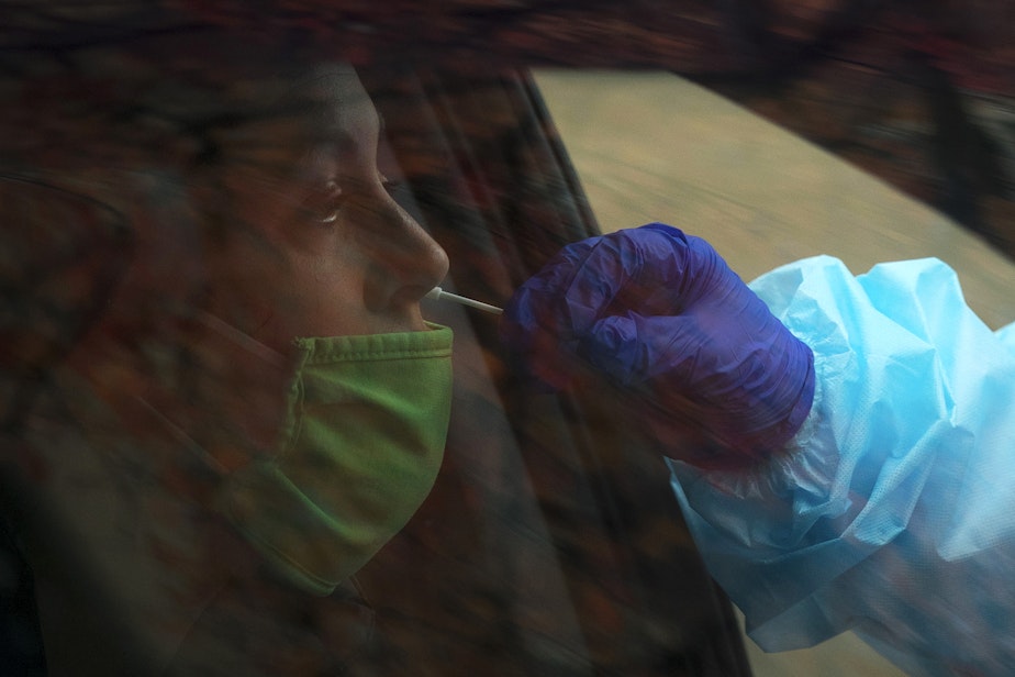caption: Registered nurse Tina Nguyen administers a Covid-19 test on Friday, November 20, 2020, at the International Community Health Services drive thru testing site on 8th Avenue South in Seattle's International District.