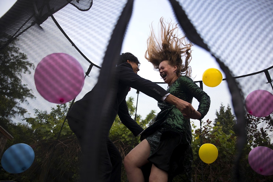 caption: Leo Padua, a 17-year-old senior at Ingraham High School, and Morgen White, right, an 18-year-old senior at Ballard High School, jump on a trampoline with balloons during their own prom celebration in Leo's backyard on Saturday, May 23, 2020, in Seattle.